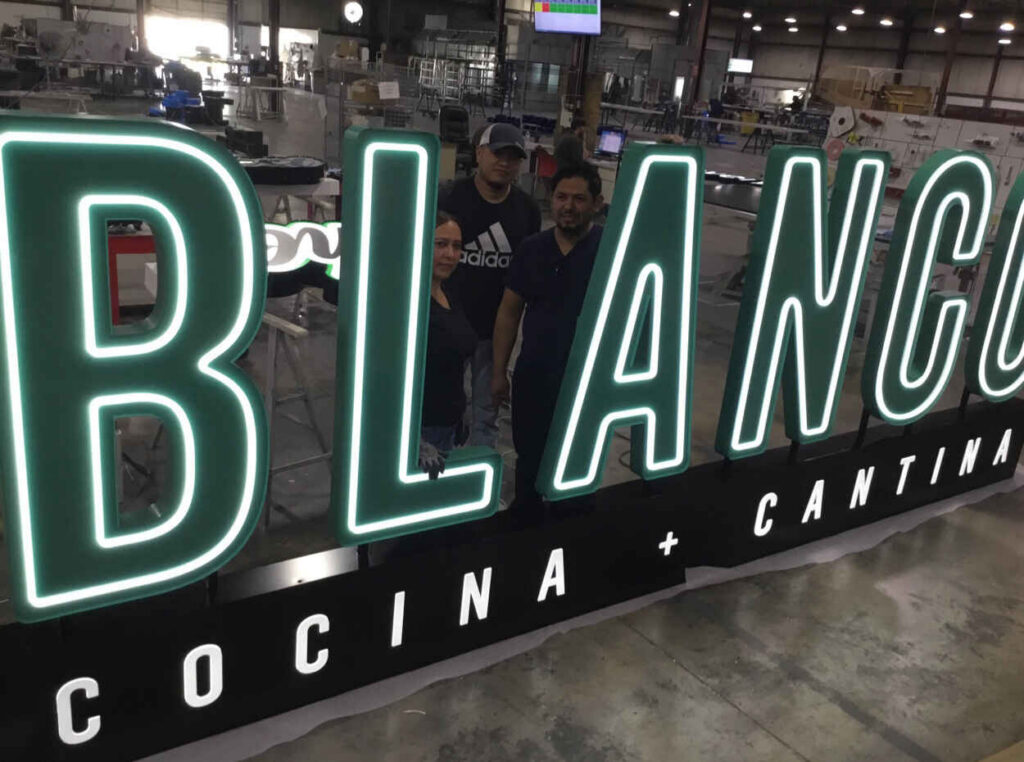 Large illuminated channel letters undergoing final inspection in a commercial signage factory